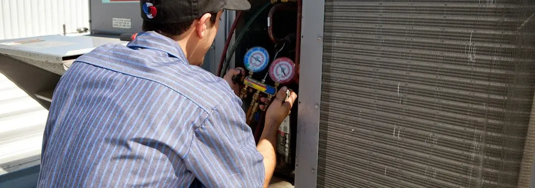 HVAC technician servicing a condenser unit in Green Valley